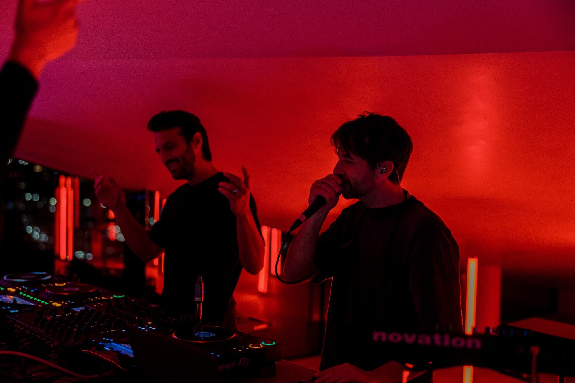 Zwei DJs legen im roten Licht auf.