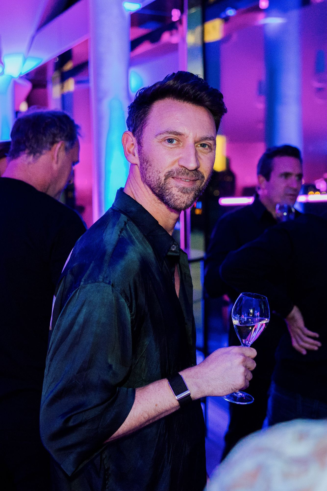 Gast mit Champagnerglas im violetten Licht.
