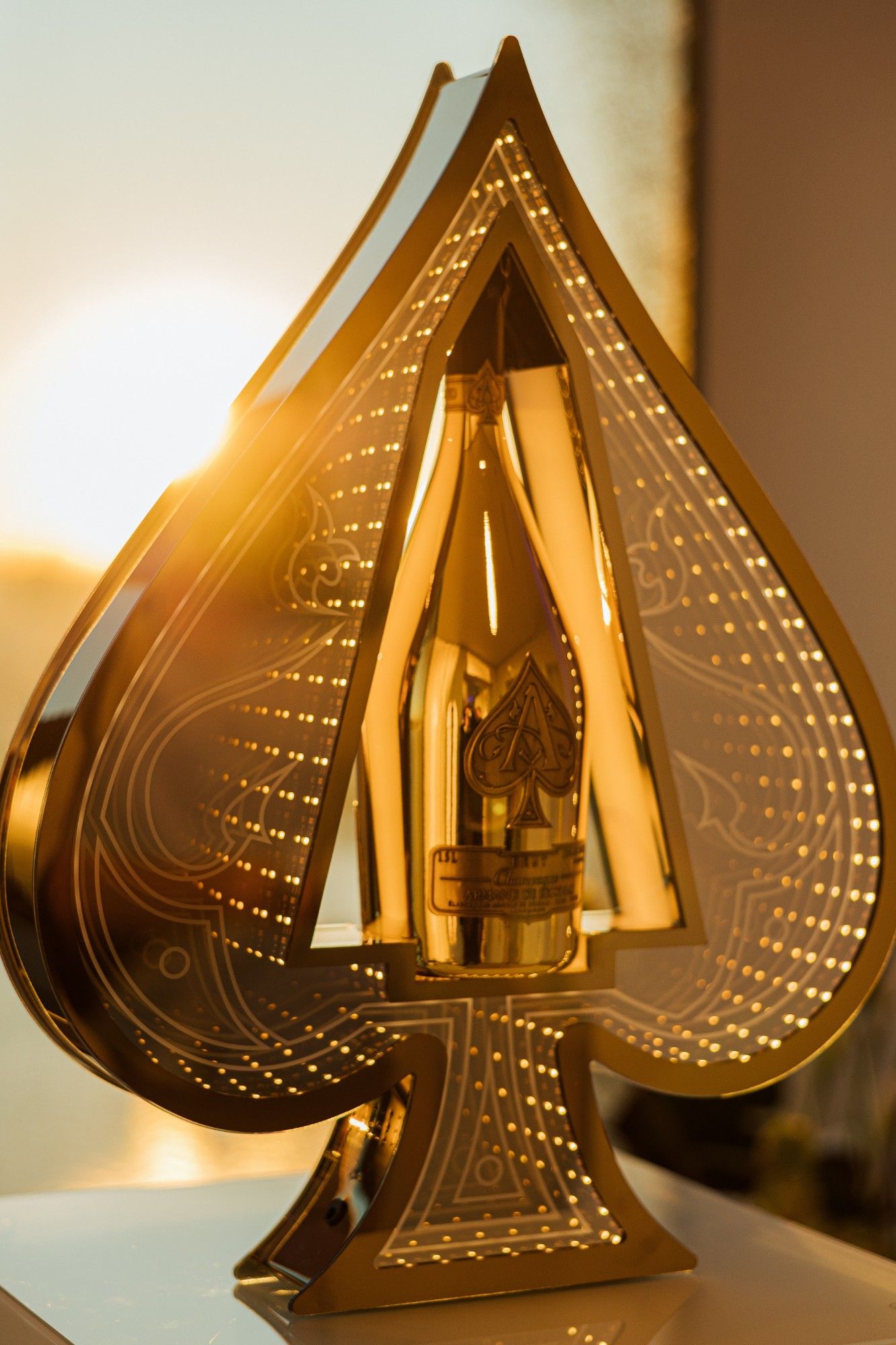 Goldene Flasche im beleuchteten Pik-Display.