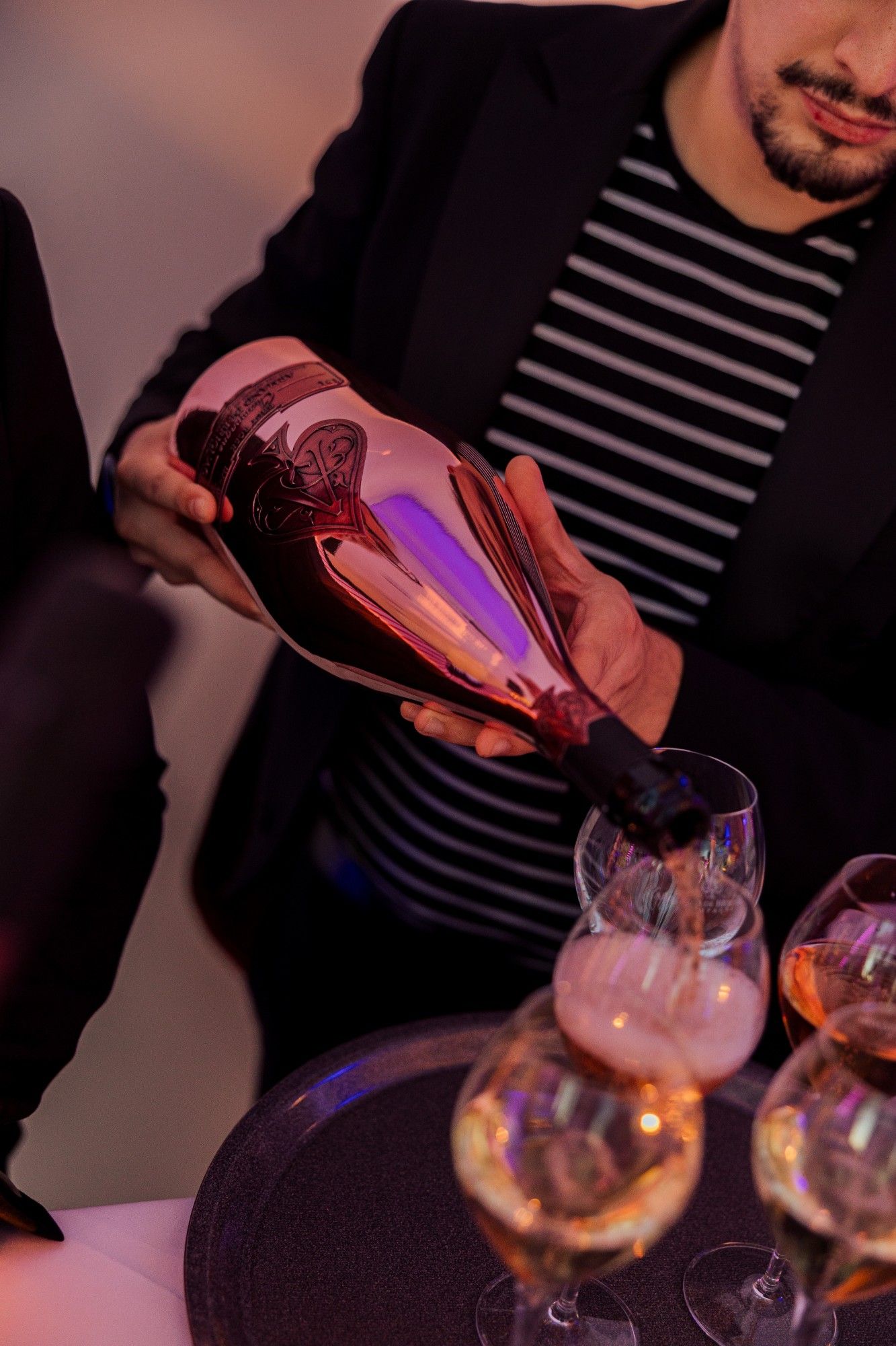 Service schenkt Champagner aus einer rosé Flasche ein.