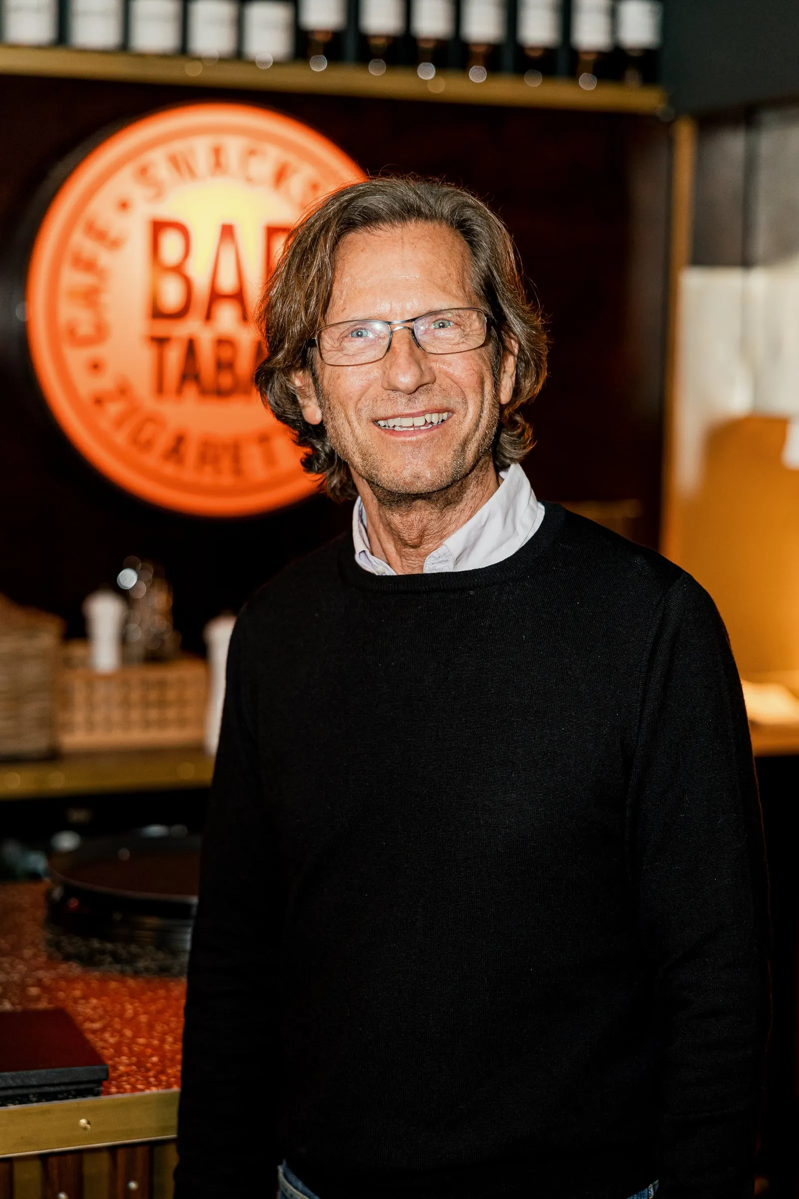 Inhaber der Bar Tabac vor dem Logo.