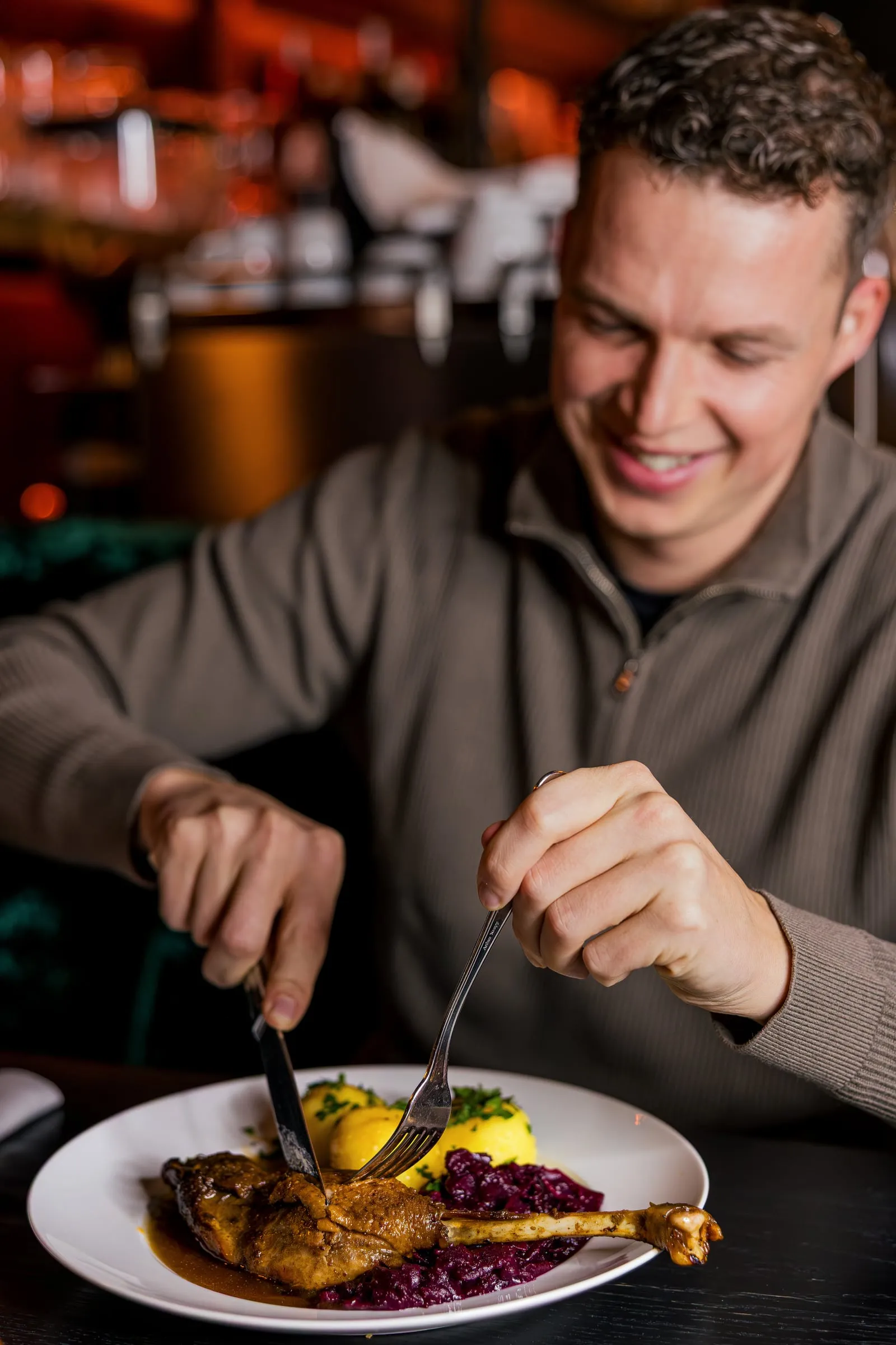 Gast schneidet Ente mit Rotkohl.
