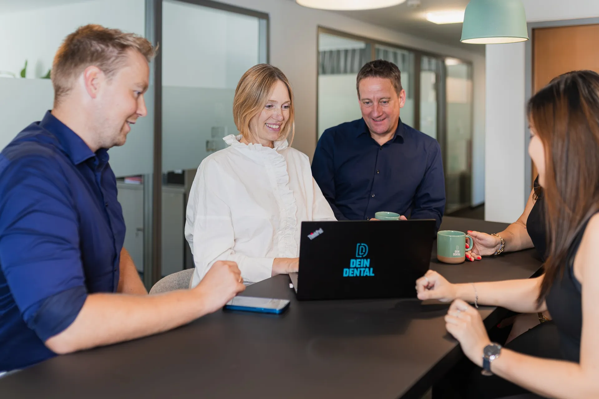 Team von Dein Dental bespricht sich am Konferenztisch mit Laptop.