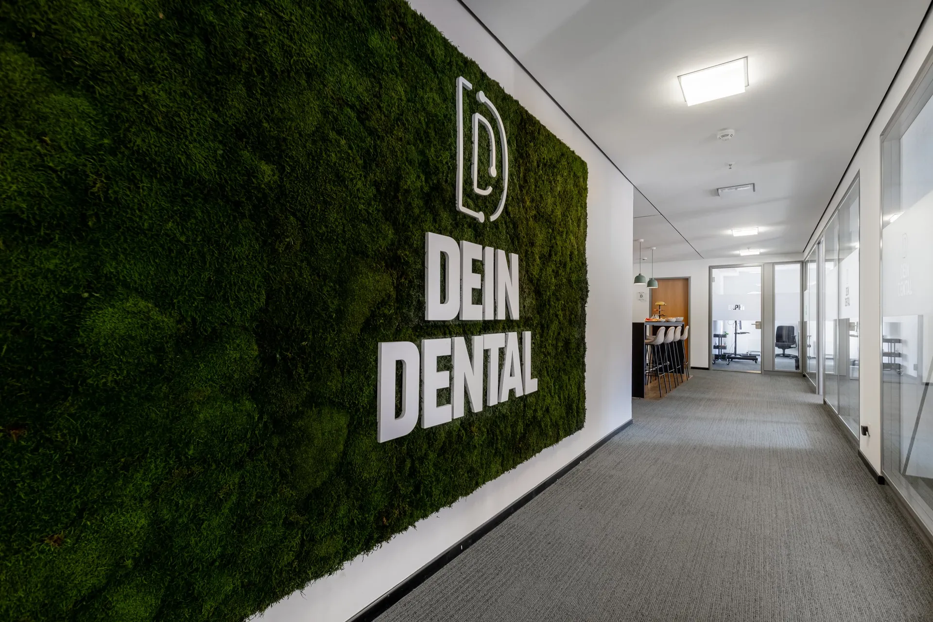 Empfangsflur mit Moos-Wand und Dein-Dental-Logo.
