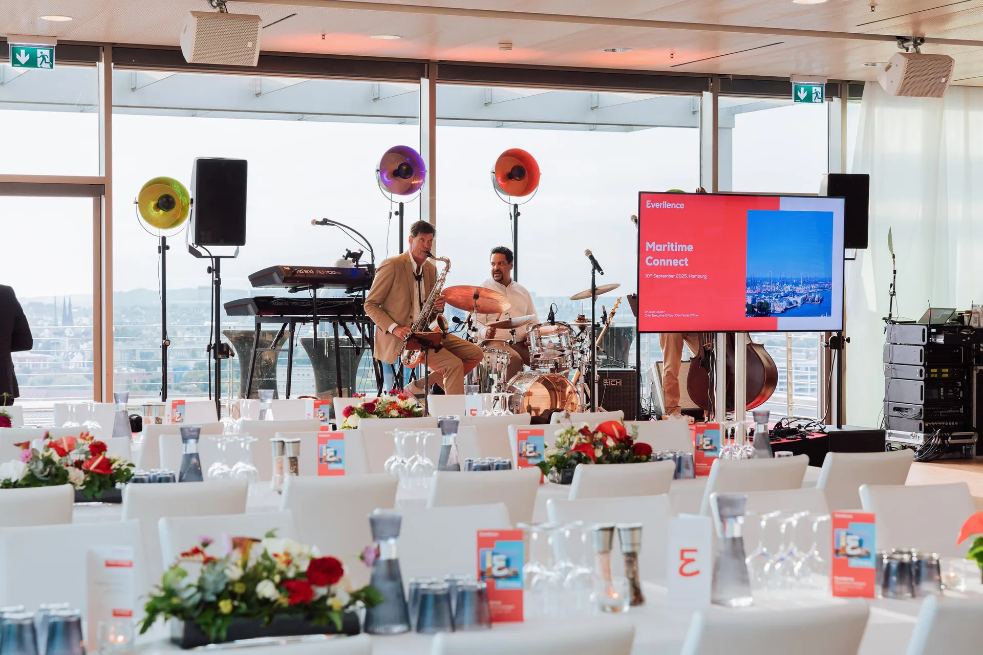 Eventfläche mit Bühne, Band und gedeckten Tischen über dem Hafen.