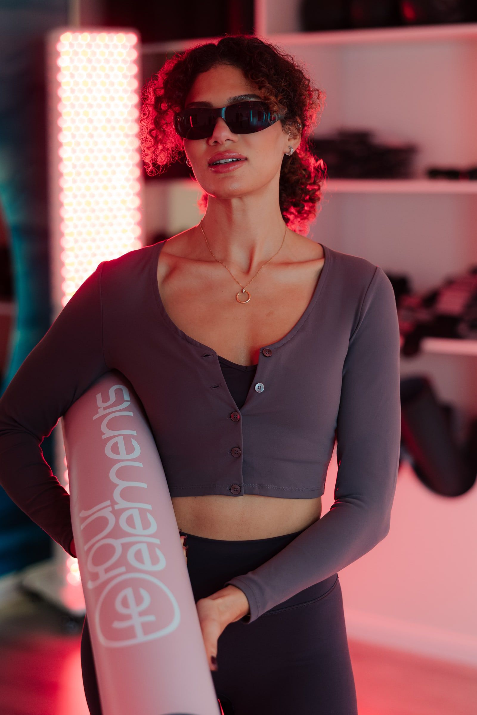 Teilnehmerin mit Sonnenbrille und Matte unter dem Arm im roten Licht.