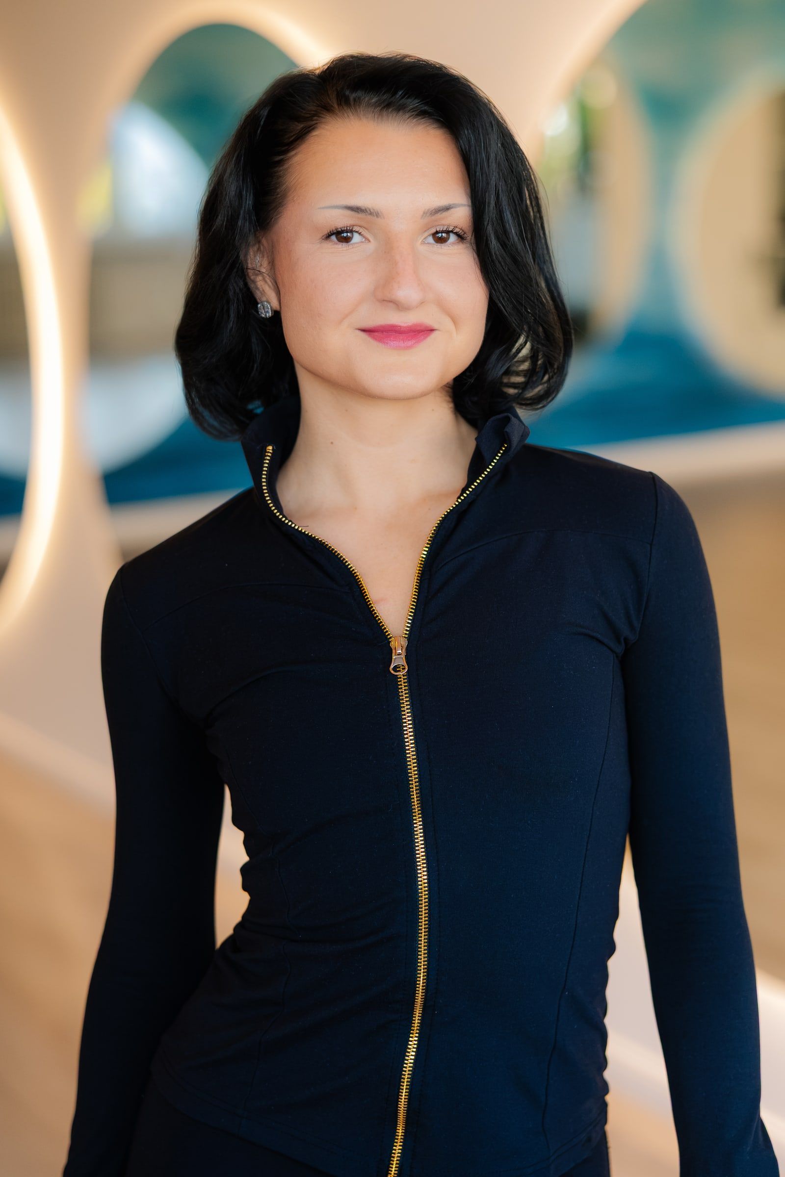 Portrait einer Trainerin in schwarzer Jacke im Studio.
