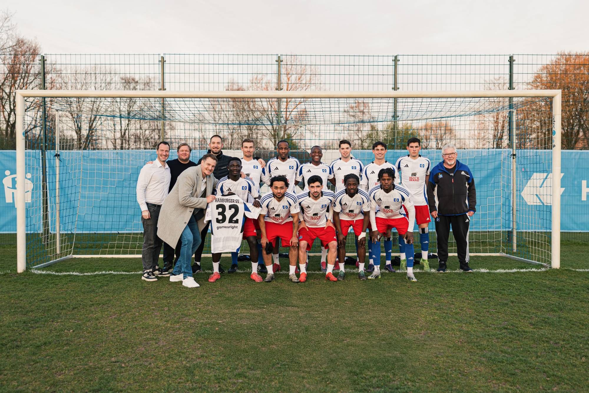 Mannschaftsfoto vor dem Tor mit Spielern, Trainer und Gästen, vorne das Trikot mit der Nummer 32.