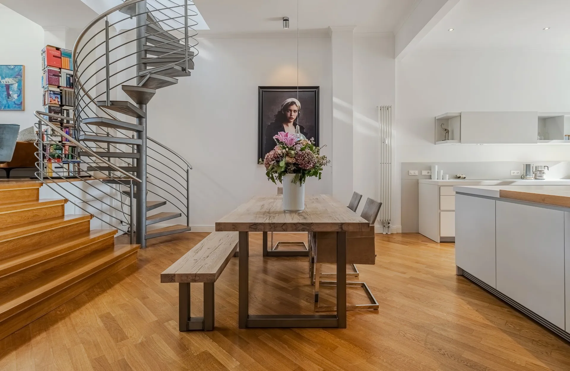 Essbereich mit Holztisch, Wendeltreppe und offener Küche.