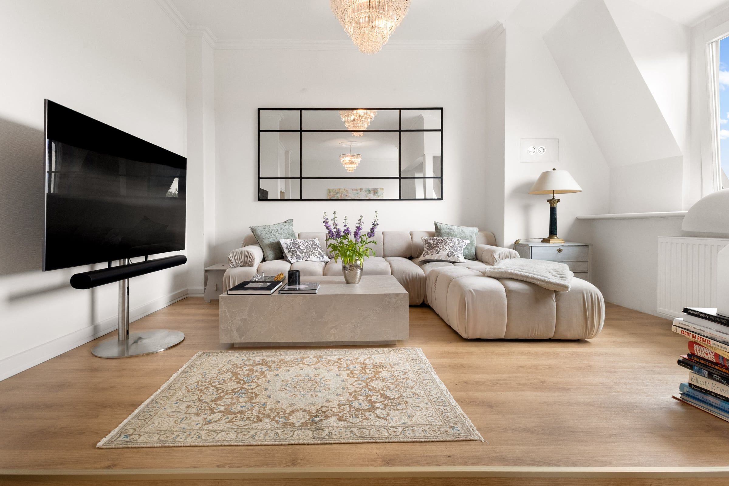 Wohnzimmer mit Sofa, Teppich und Kronleuchter unter Dachschrägen.