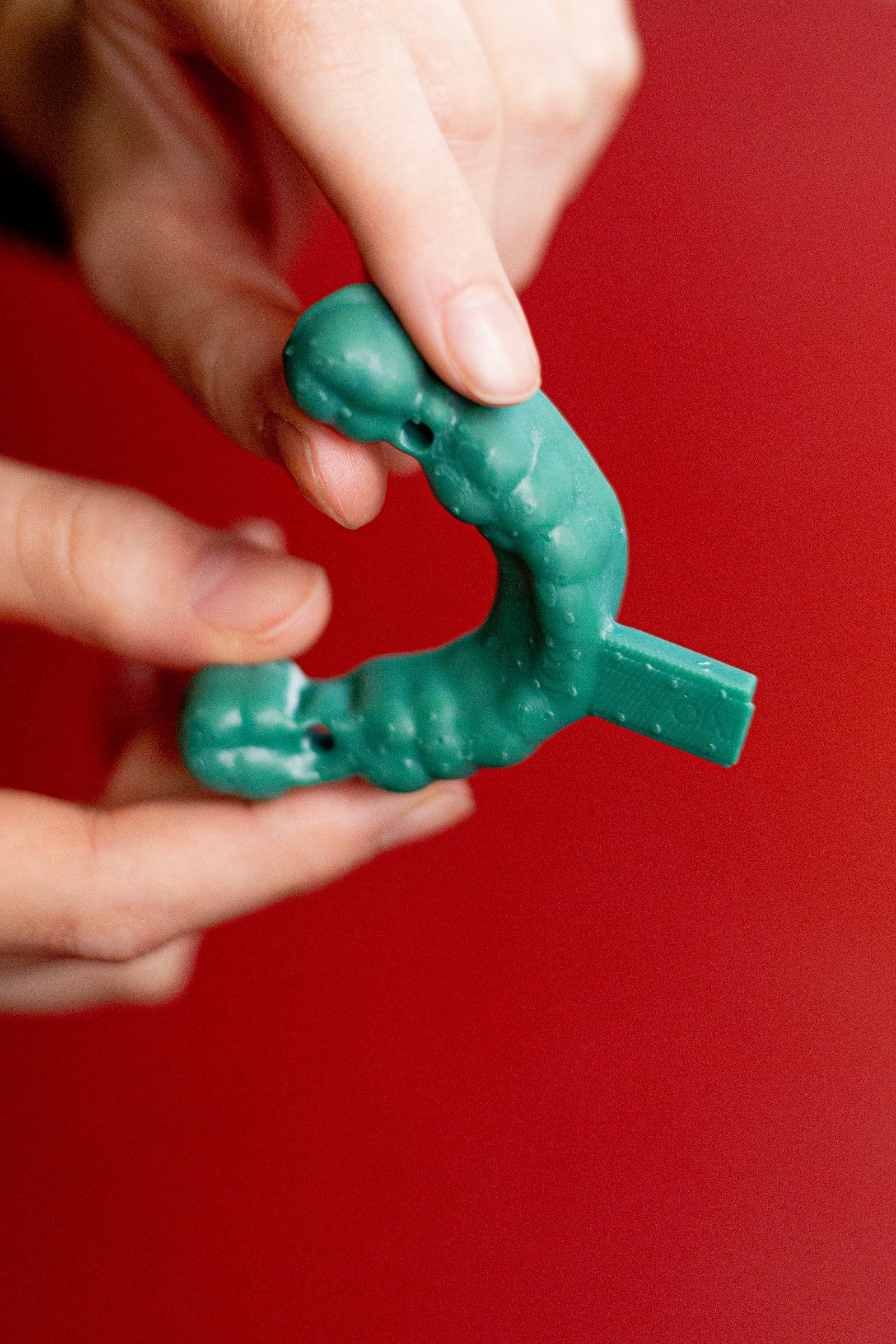 Hände halten ein grünes 3D-gedrucktes Modell.