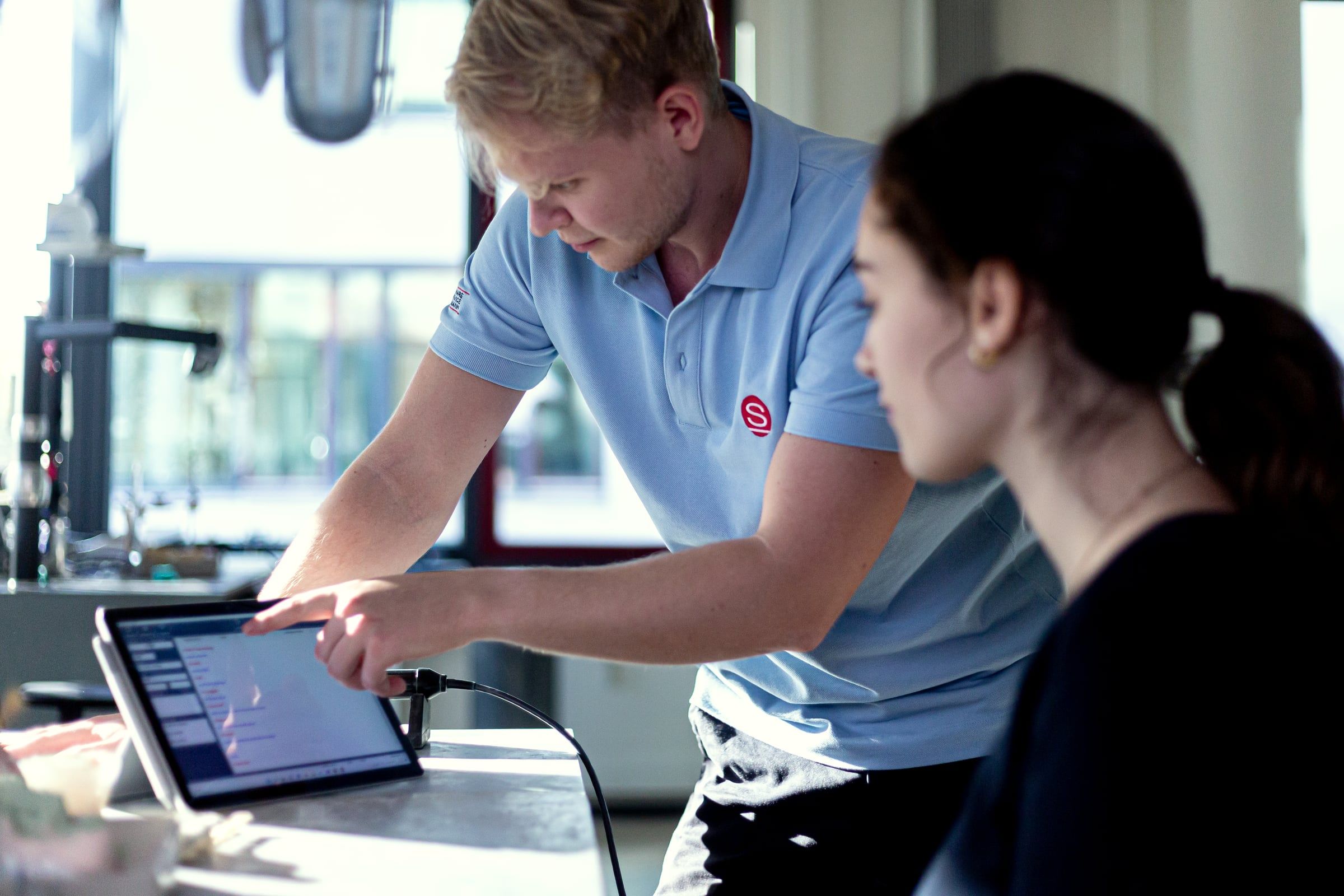 Berater zeigt einer Zahntechnikerin die Software auf dem Tablet.