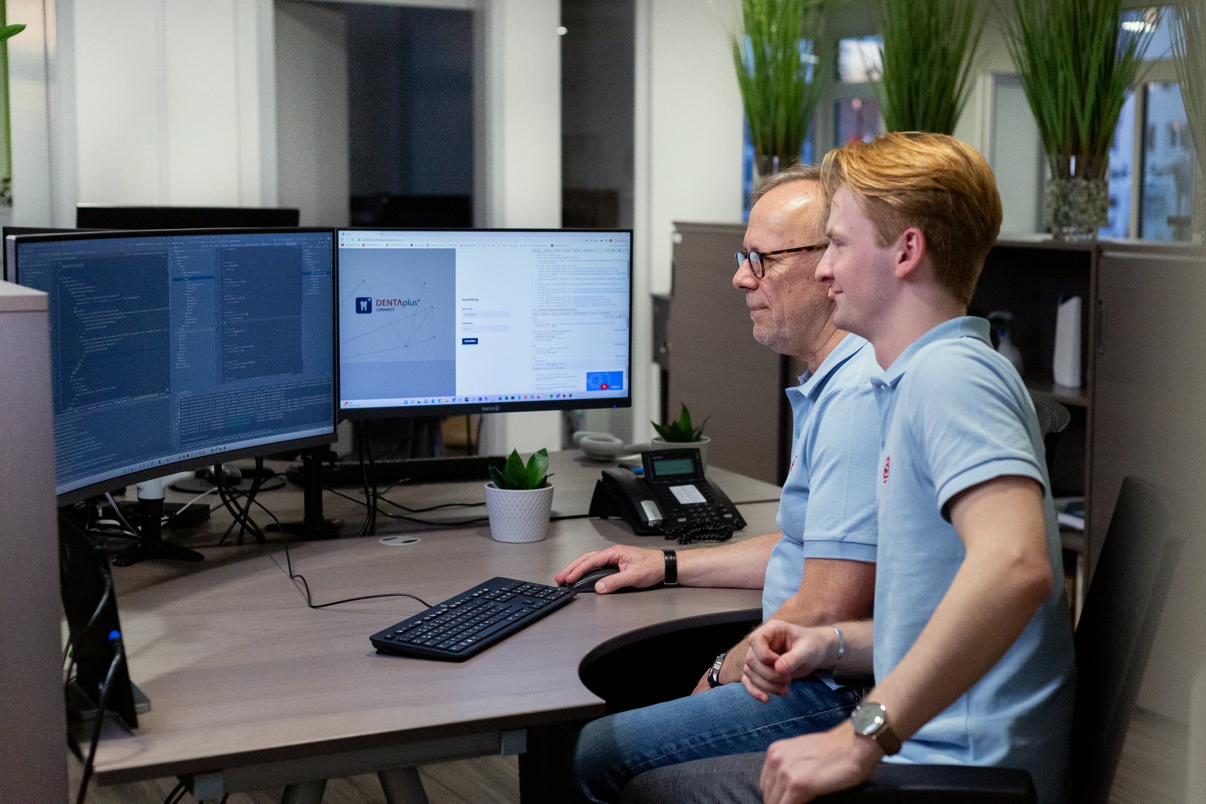Zwei Kollegen besprechen sich vor großen Monitoren.