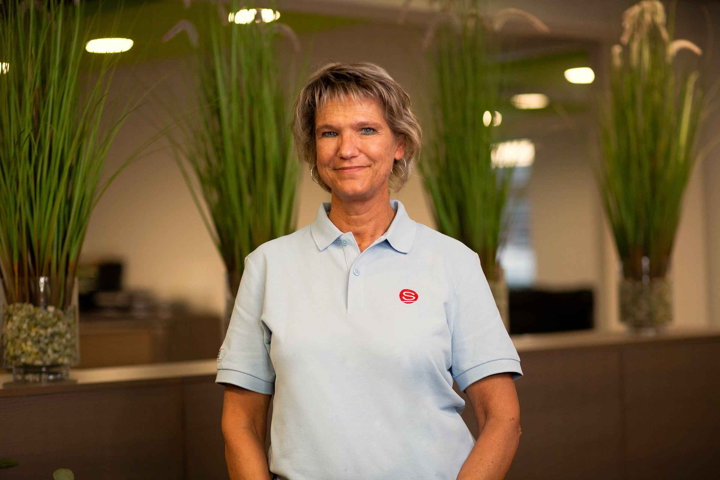 Portrait einer Mitarbeiterin im hellblauen Poloshirt.