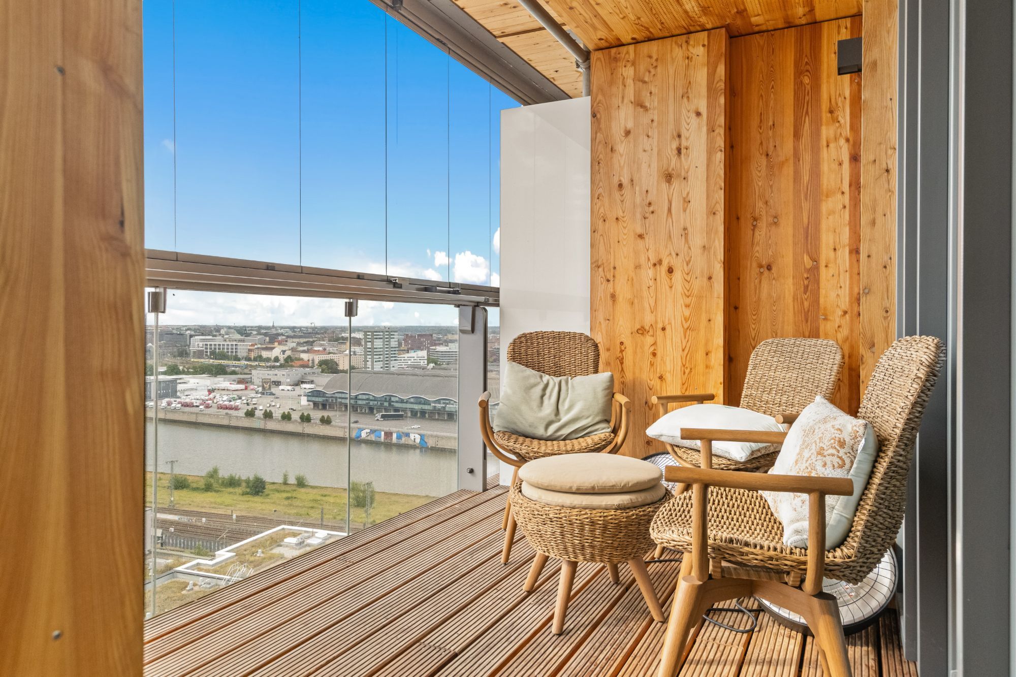 Loggia mit Holzverkleidung und Rattansesseln, dahinter Hafen und Großmarkthalle.